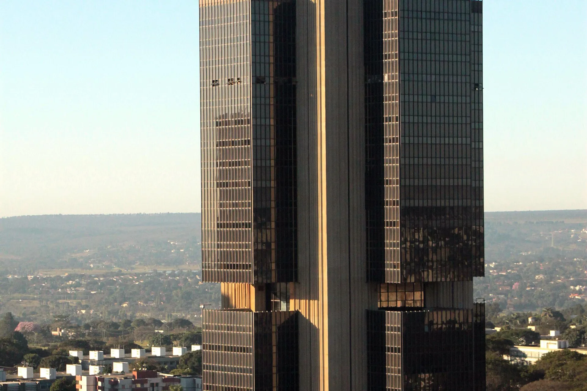 Torre de vidro escuro e concreto da sede do Banco Central do Brasil, em Brasília, sob céu azul