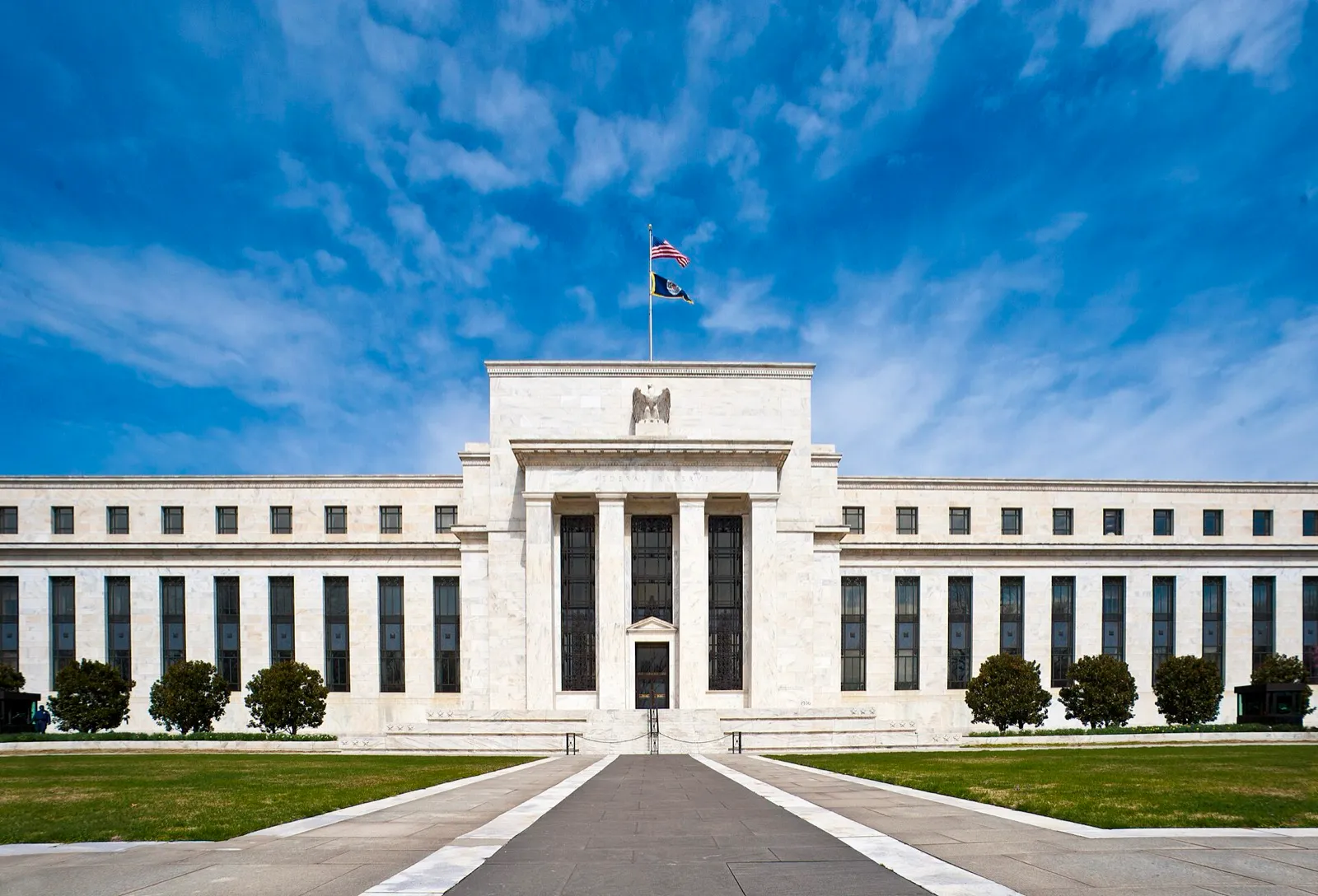 Fachada de mármore branco do edifício Marriner S. Eccles, sede do Federal Reserve, em Washington, sob céu azul