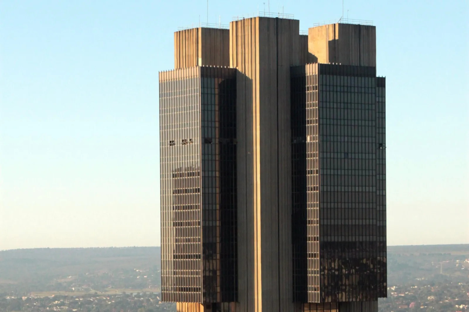 Torre da sede do Banco Central do Brasil, em Brasília, com fachada de vidro escuro e concreto sob céu azul.