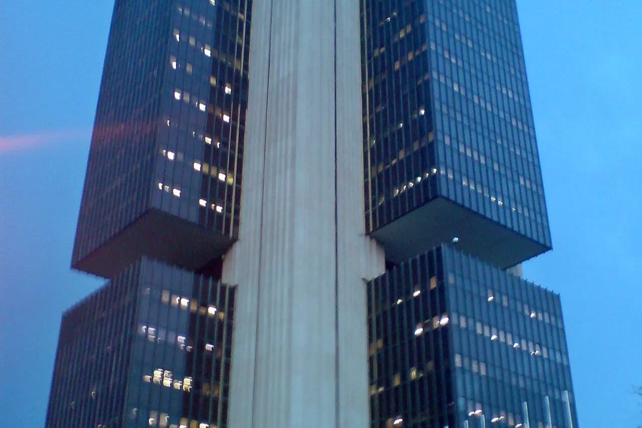 Fachada do edifício-sede do Banco Central, em Brasília, com duas torres de vidro escuro ligadas a um núcleo central de concreto, sob céu azul